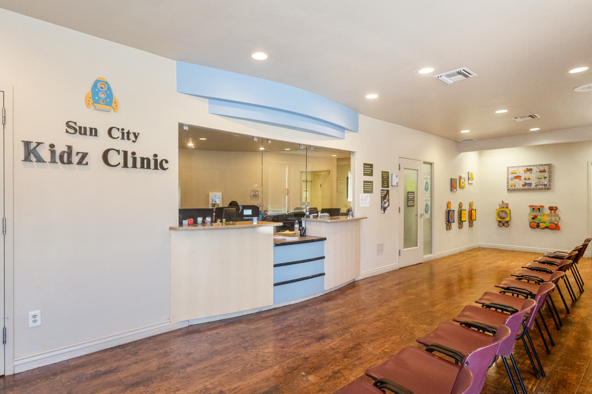 The Sun City Kidz Clinic front desk and waiting area, with children's artwork and toys on the wall